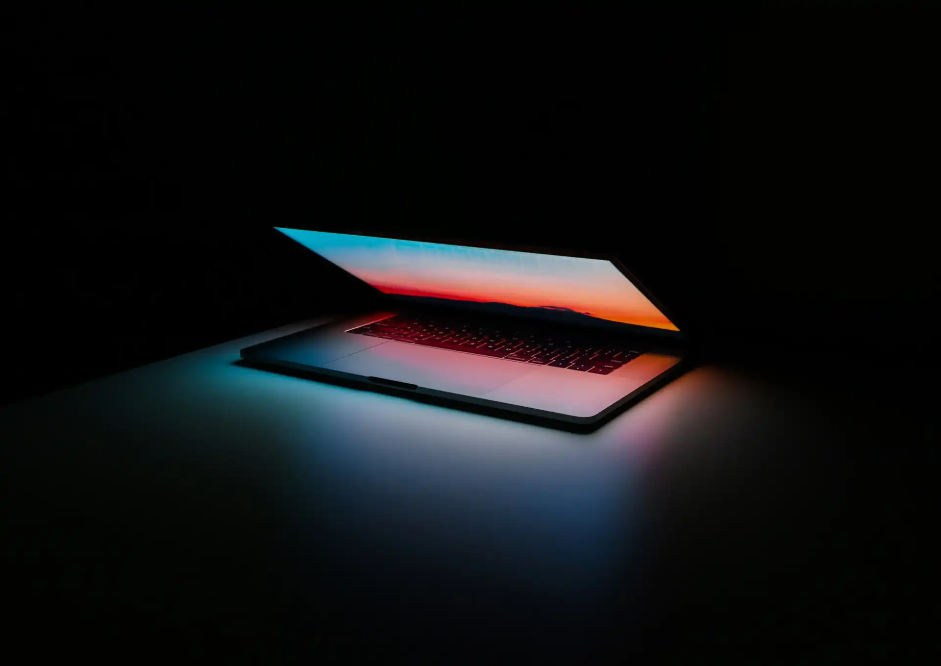 Apple laptop opened in the middle of the night creating cool light atmosphere