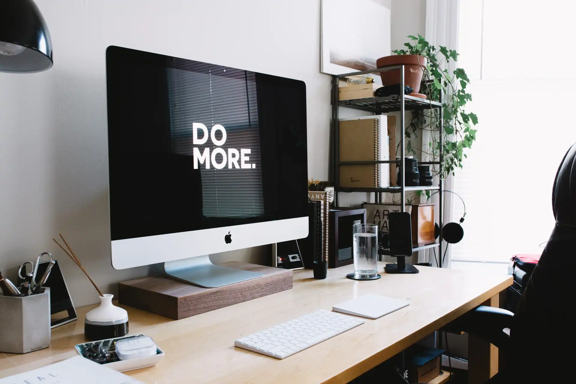 Clean work environment with Apple computer saying 'do more' on large clear screen